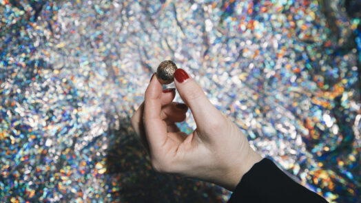 Hand mit Diagonale-Nuss vor glitzerndem Hintergrund